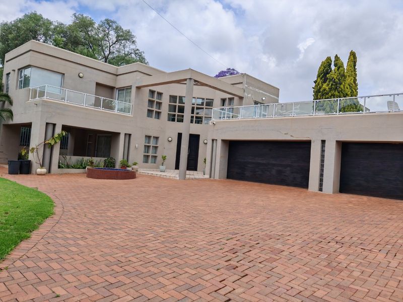 Spacious double-storey residence featuring a large paved driveway, double garage, and an expansive upper-level balcony with modern glass balustrades.