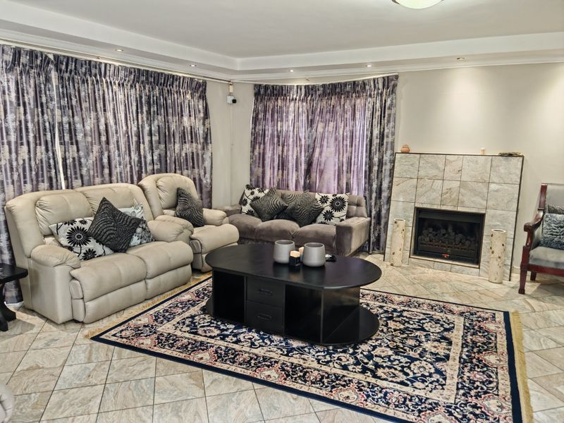 Spacious living room featuring tiled flooring, a built-in fireplace with stone-look tiling, and recessed ceiling lighting.