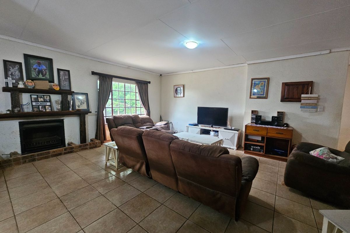 Spacious living room featuring tiled flooring and a traditional fireplace with a timber mantelpiece, offering a comfortable and functional family space.