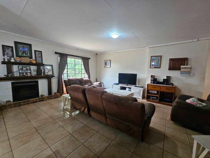 Spacious living room featuring tiled flooring and a traditional fireplace with a timber mantelpiece, offering a comfortable and functional family space.