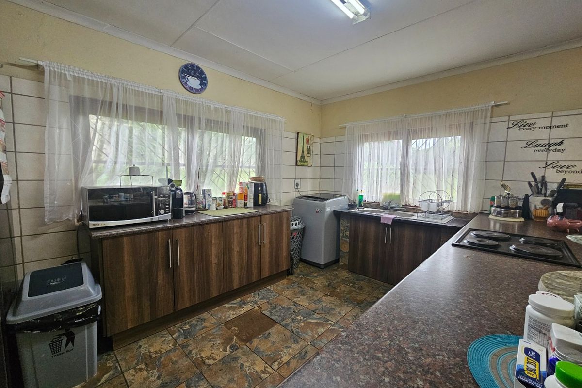 Functional kitchen featuring wood-look cabinetry, laminate countertops, a built-in electric hob, and tiled finishes throughout.