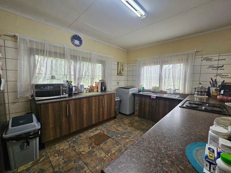 Functional kitchen featuring wood-look cabinetry, laminate countertops, a built-in electric hob, and tiled finishes throughout.