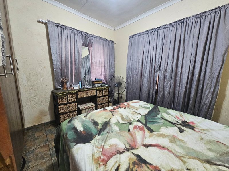 A bedroom featuring tiled flooring, coved ceilings, and a built-in wardrobe, showing signs of wear on the wall surfaces.