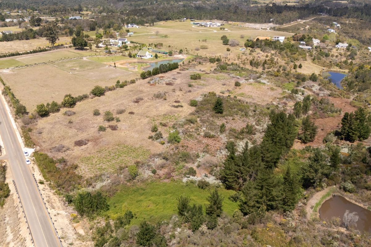 An aerial view of a large, undeveloped residential land parcel featuring natural vegetation, proximity to a main road, and a small dam.