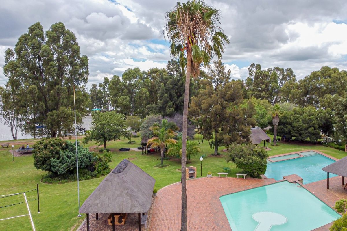Aerial view of a spacious property featuring a swimming pool, multiple thatched lapas, brick-paved entertainment areas, and expansive landscaped gardens.
