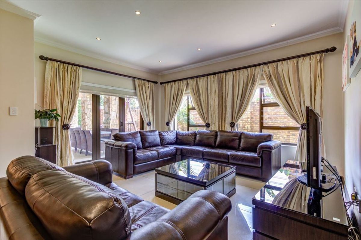 Spacious living room featuring tiled flooring, recessed downlighting, and large sliding glass doors providing access to the outdoor patio area.