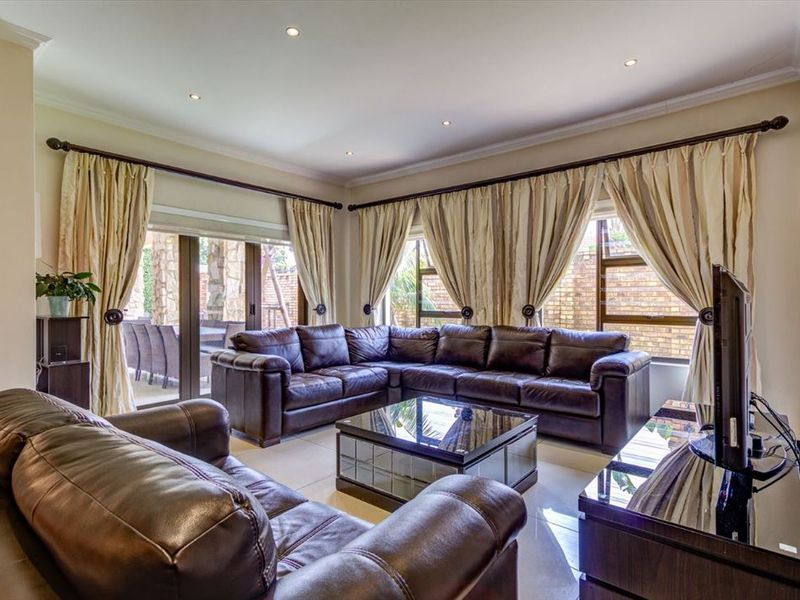 Spacious living room featuring tiled flooring, recessed downlighting, and large sliding glass doors providing access to the outdoor patio area.