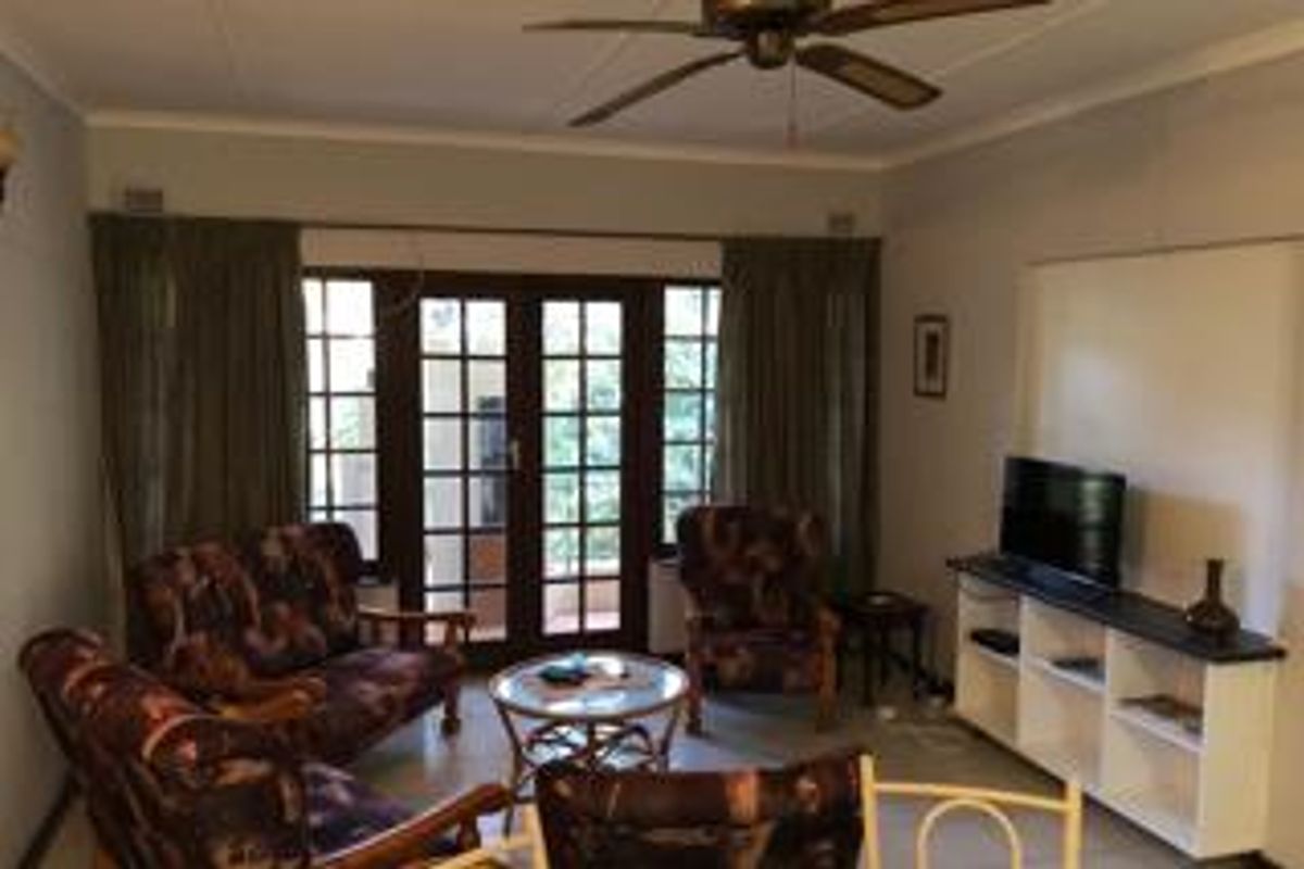 A living room featuring a ceiling fan and French doors that open to an outdoor area, providing natural light and access.