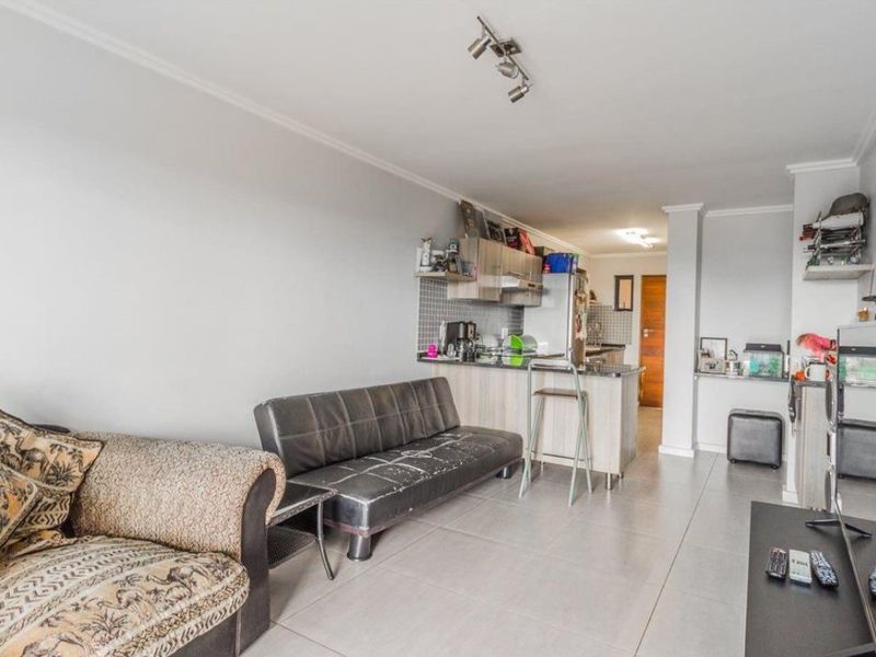 Open-plan living area featuring a compact kitchen with granite countertops, breakfast counter, and tiled flooring throughout.