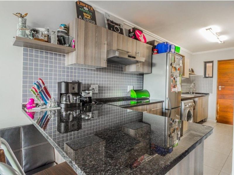 A functional kitchen featuring granite countertops, tiled backsplash, and ample built-in cabinetry, providing a practical workspace for daily cooking and meal preparation.