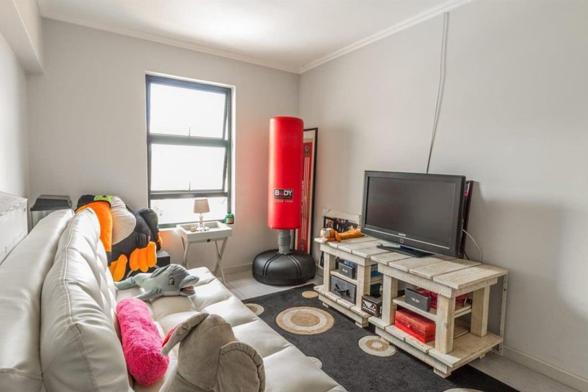 A functional living room featuring tiled flooring, coved ceilings, and an aluminium window frame, providing a neutral base for potential interior updates.
