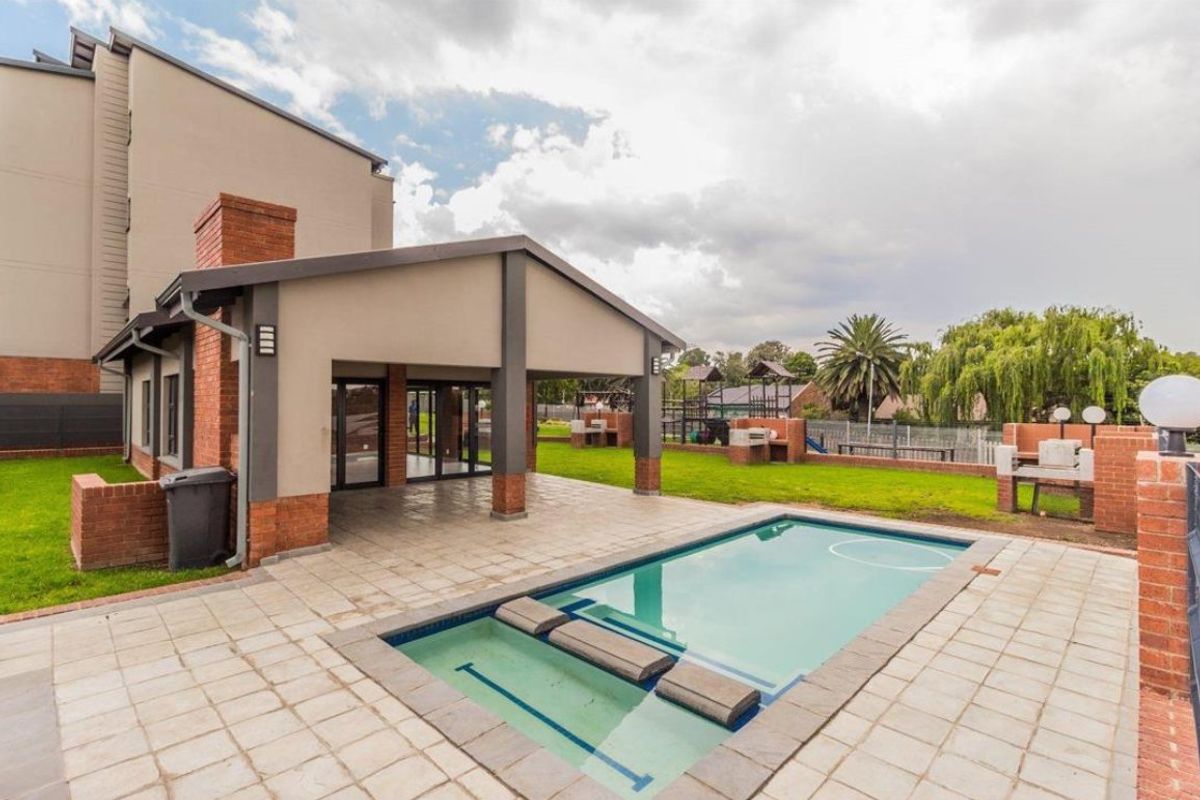 Communal outdoor area featuring a swimming pool, covered patio with built-in braai facilities, and landscaped garden space.