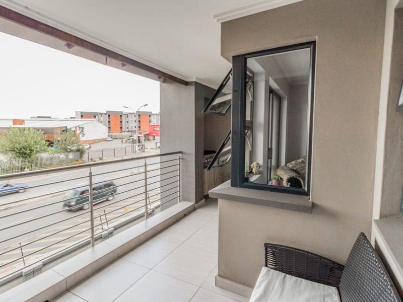 A modern covered balcony featuring tiled flooring, a stainless steel balustrade, and views over the surrounding streetscape.