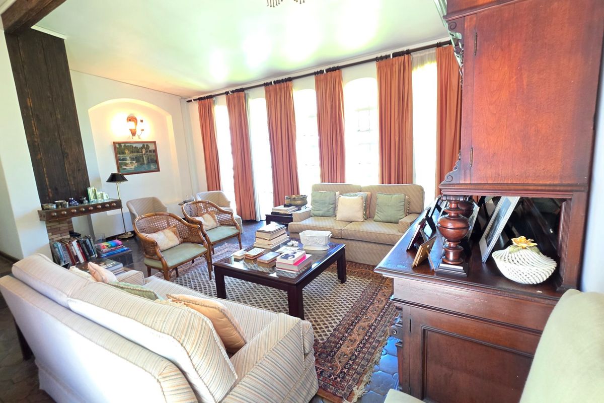 Spacious living room featuring tiled flooring, an arched wall niche, and large windows with natural light, creating a warm and inviting atmosphere.