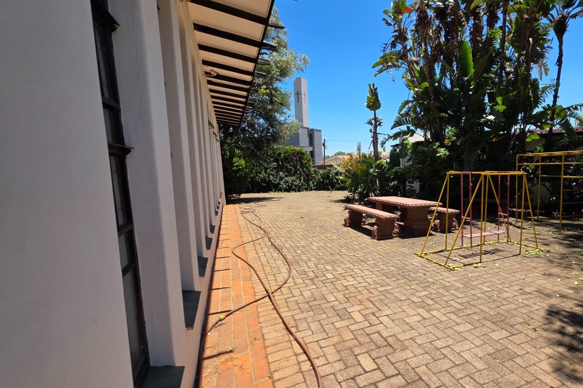 A paved rear patio area featuring a brick border and overhanging roof eaves, providing a functional outdoor space.