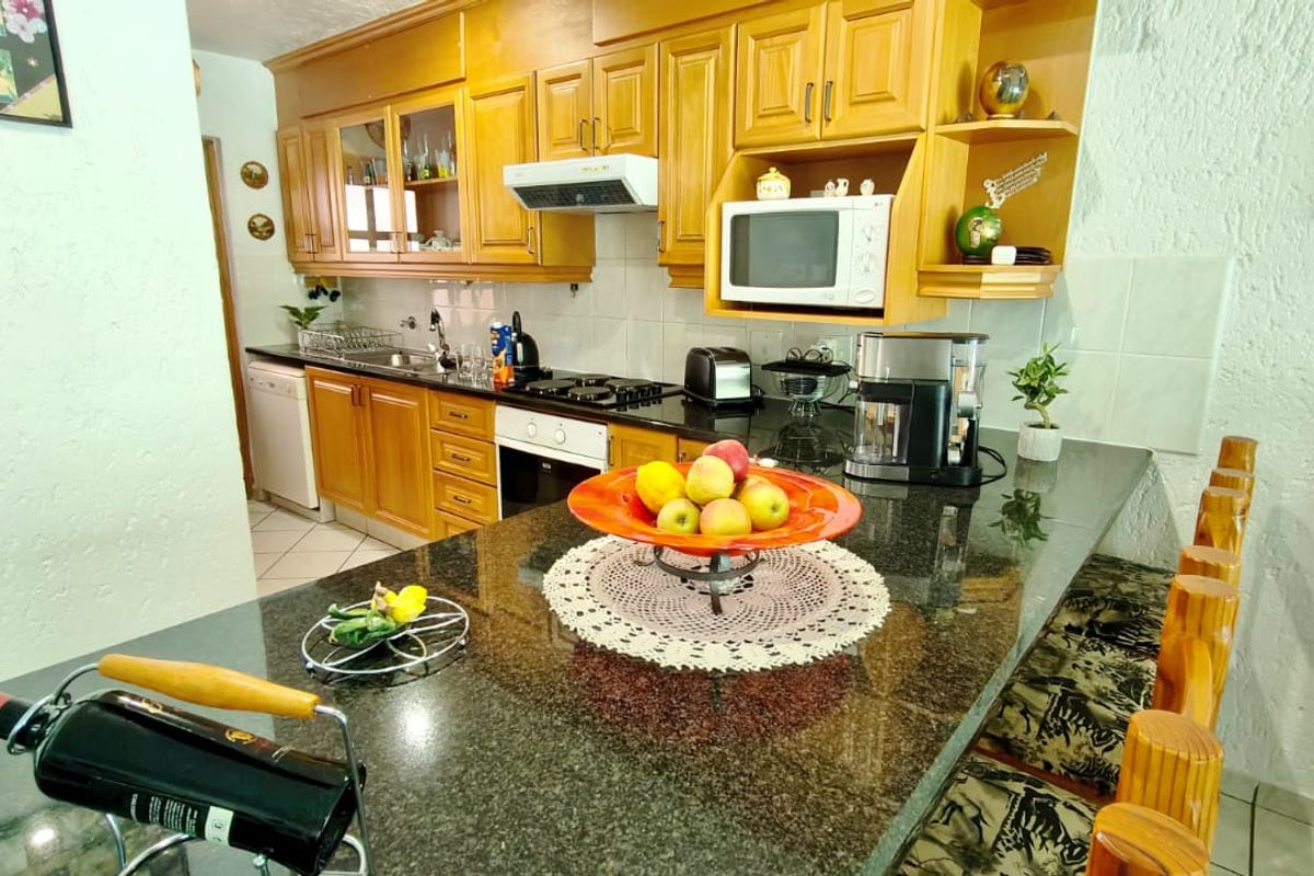 A functional kitchen featuring warm-toned wooden cabinetry, granite countertops, a breakfast bar, and integrated appliances, offering a classic and practical cooking space.
