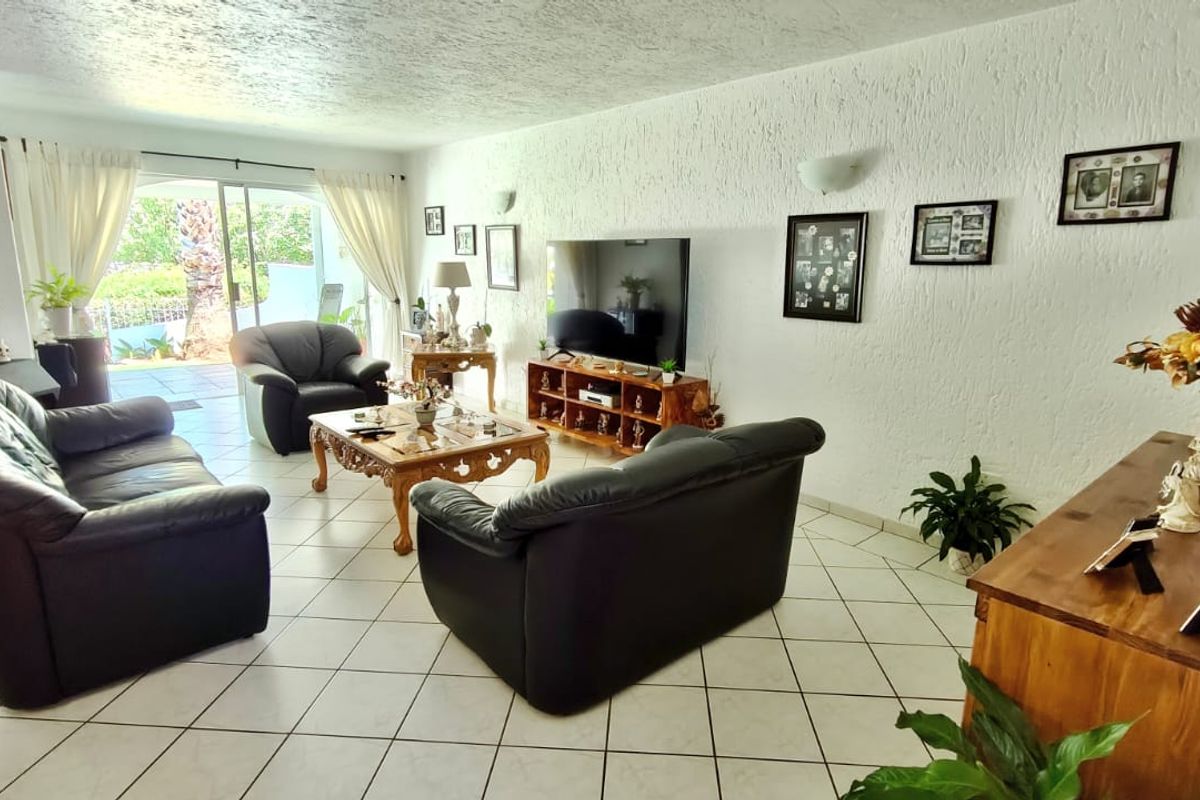 Spacious living room featuring tiled flooring, textured walls, and a large sliding glass door providing access to the outdoor area.