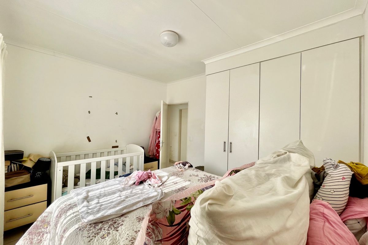 A bedroom featuring built-in wardrobes and coved ceiling detailing, providing a functional space with potential for cosmetic updates.