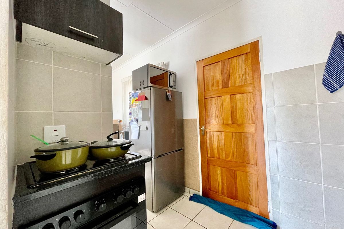 A functional kitchen area featuring tiled splashbacks, a built-in stove, and a solid timber door leading to an adjacent space.