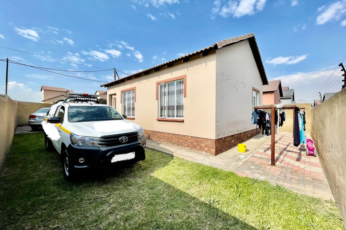 Rear view of the house featuring a paved area, small lawn, and perimeter boundary walls.