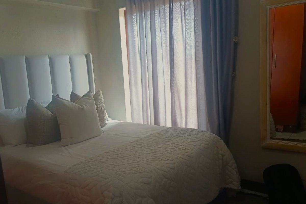 A cozy bedroom featuring a built-in cupboard and natural light filtering through curtains, providing a comfortable and functional sleeping space.