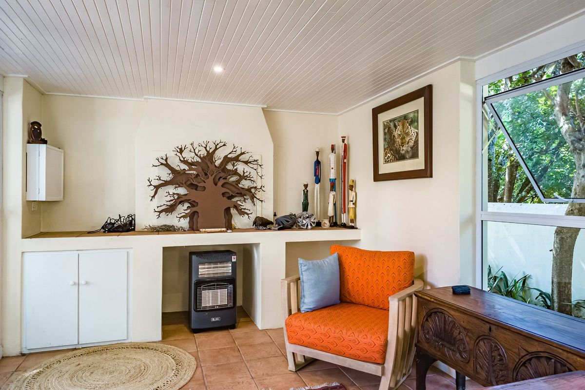 A living area featuring a built-in masonry fireplace, tiled flooring, and a tongue and groove ceiling with natural light from the adjacent window.