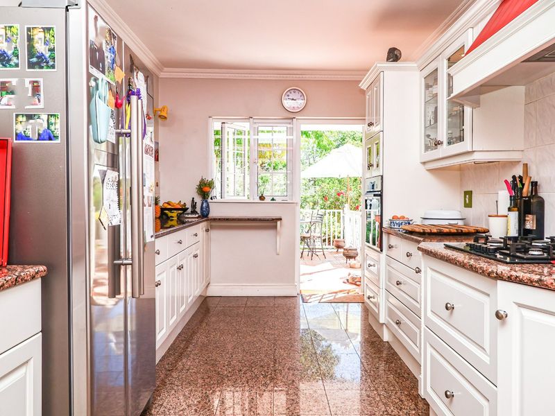 A functional kitchen featuring granite countertops, white cabinetry, built-in appliances, and direct access to an outdoor patio area.