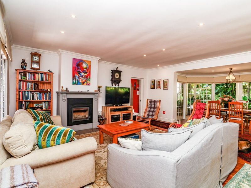 Spacious open-plan living and dining area featuring a fireplace, hardwood flooring, and large windows providing natural light and garden views.