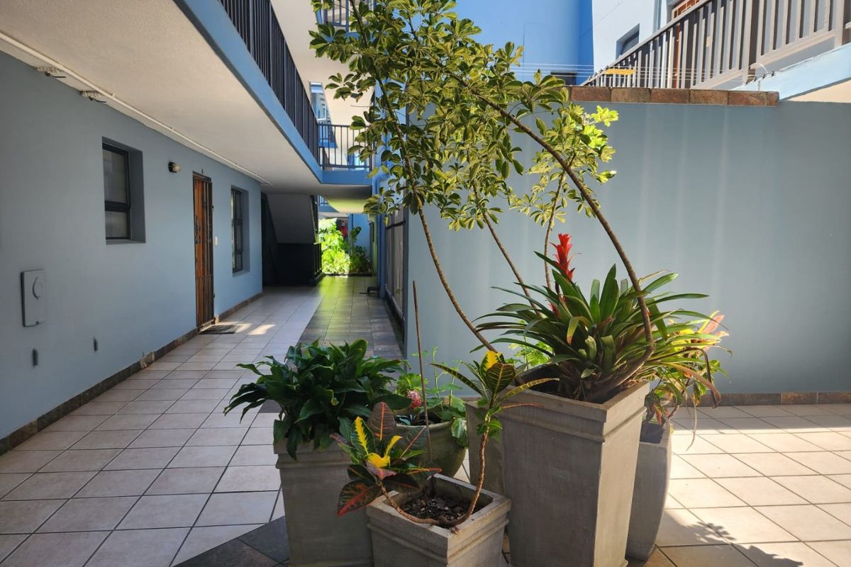 A well-maintained outdoor courtyard area within an apartment complex, featuring tiled flooring and access to building walkways.