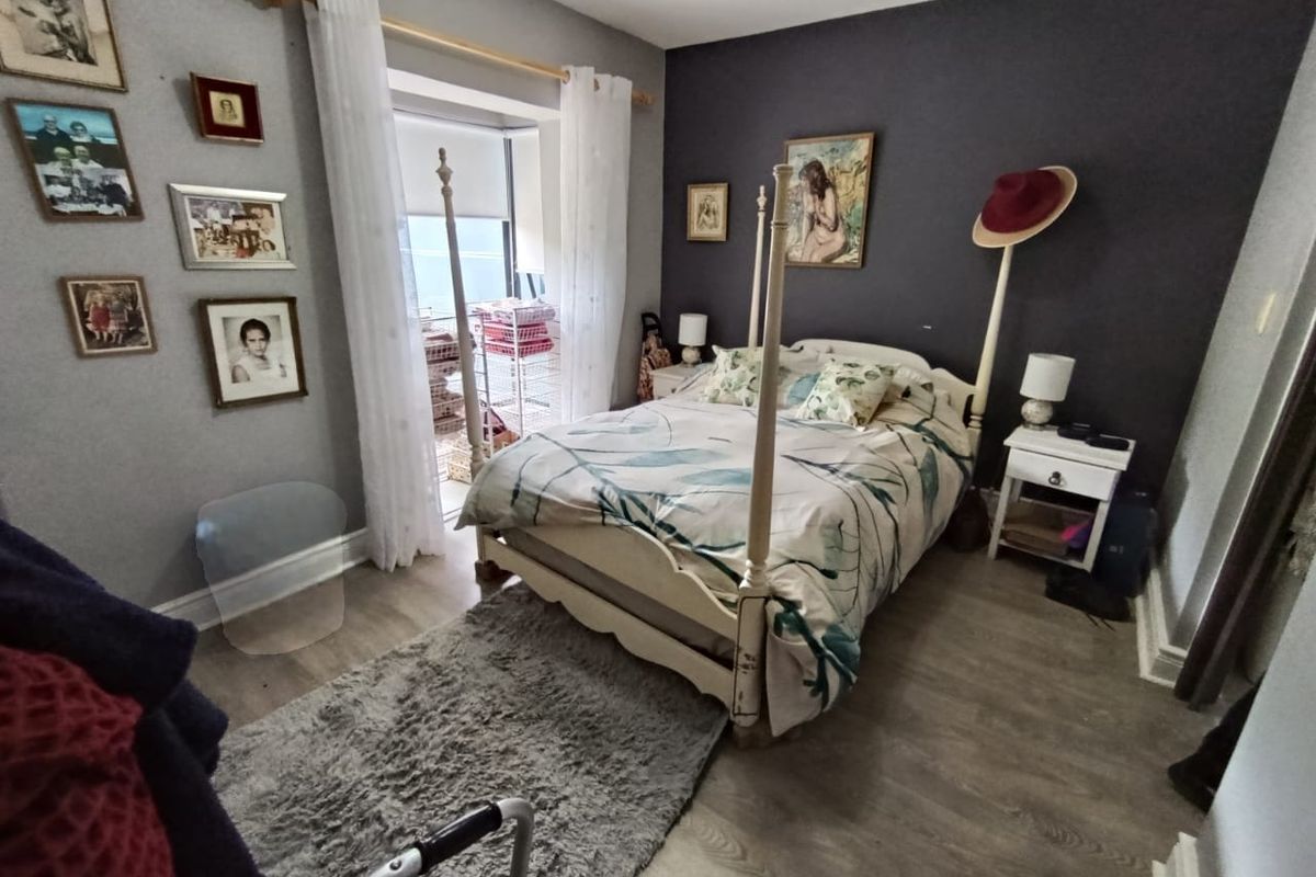 A bedroom featuring laminate flooring, a dark accent wall, and a sliding glass door providing access to a balcony.
