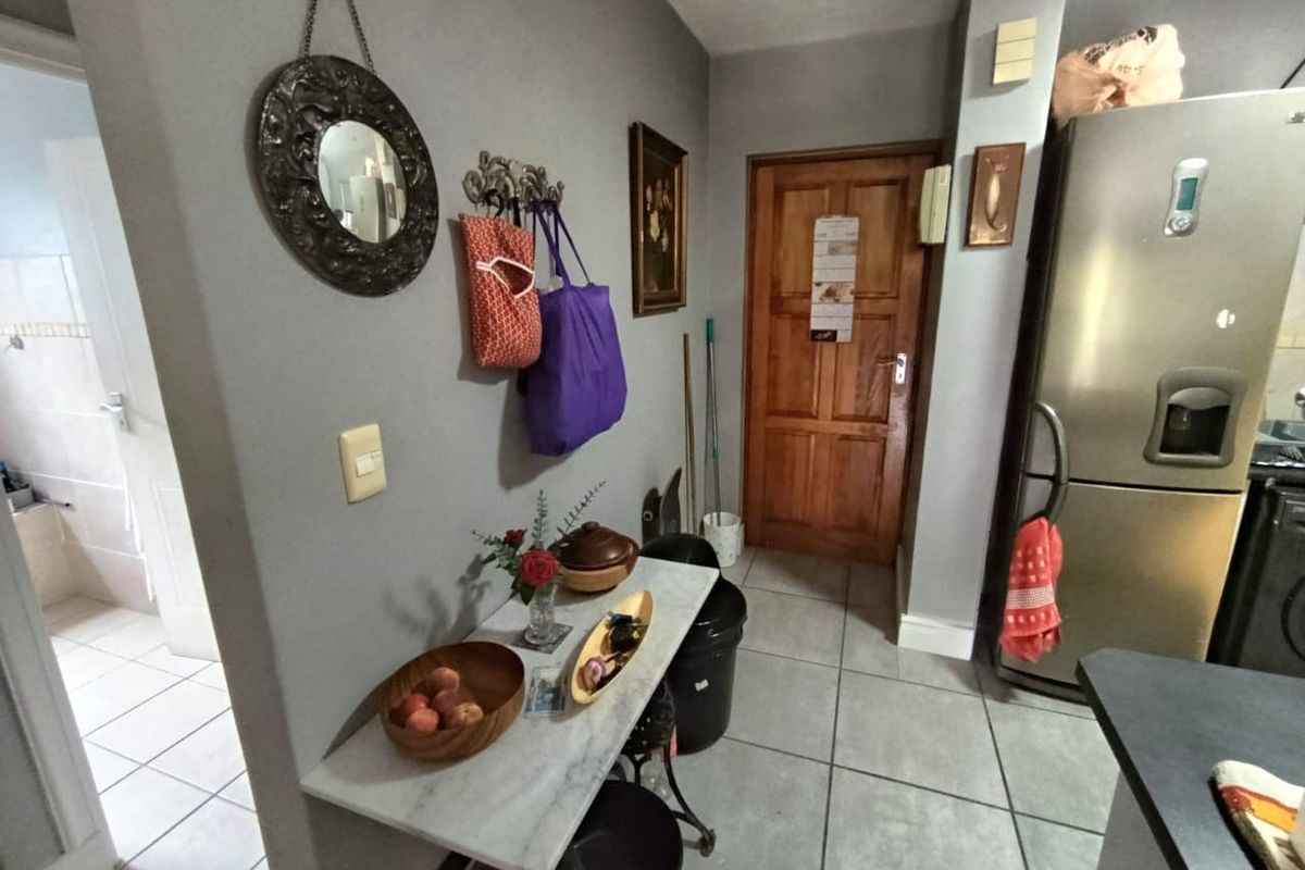 A functional kitchen area featuring tiled flooring, a stone-topped console table, and a solid wood door leading to an adjacent room.