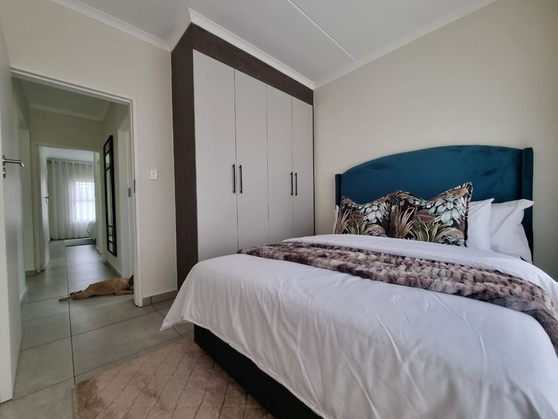 A well-maintained bedroom featuring neutral tiled flooring, coved ceilings, and modern built-in cupboards with a clean, contemporary finish.