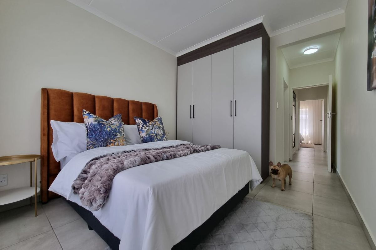 A well-maintained bedroom featuring neutral tiled flooring, a modern built-in wardrobe, and coved ceiling details, providing a clean and functional living space.