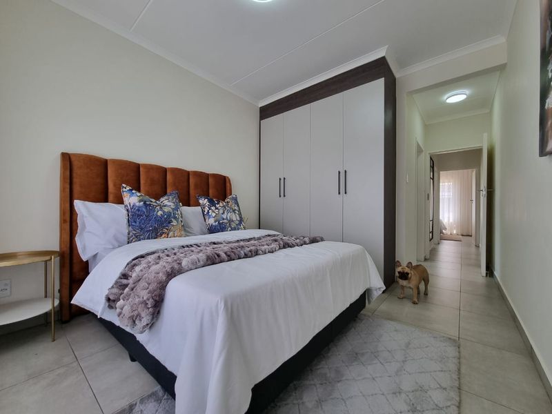A well-maintained bedroom featuring neutral tiled flooring, a modern built-in wardrobe, and coved ceiling details, providing a clean and functional living space.