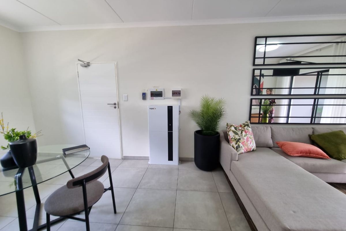 A bright living area featuring neutral tiled flooring and a wall-mounted inverter system, providing a clean and functional space.