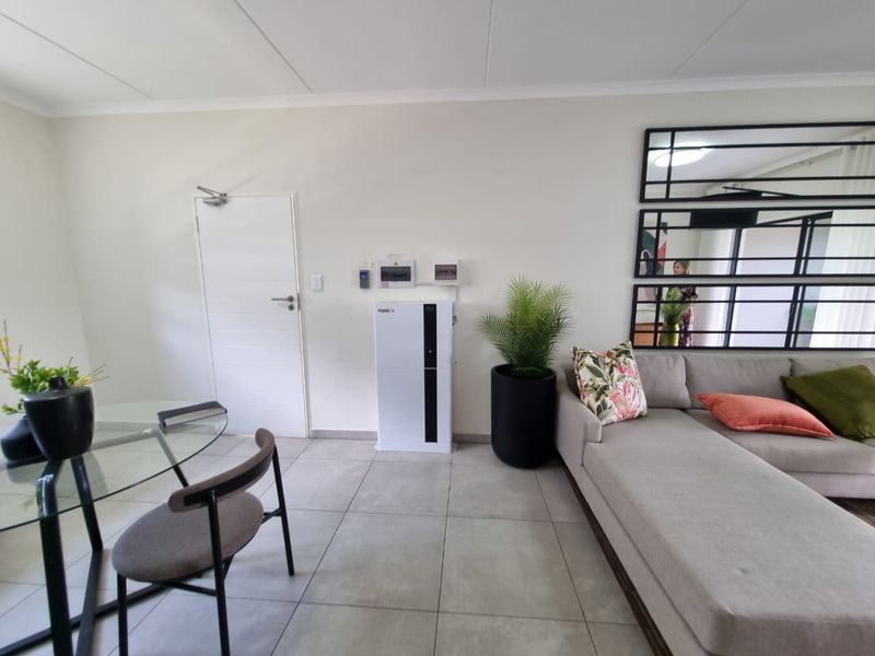 A bright living area featuring neutral tiled flooring and a wall-mounted inverter system, providing a clean and functional space.