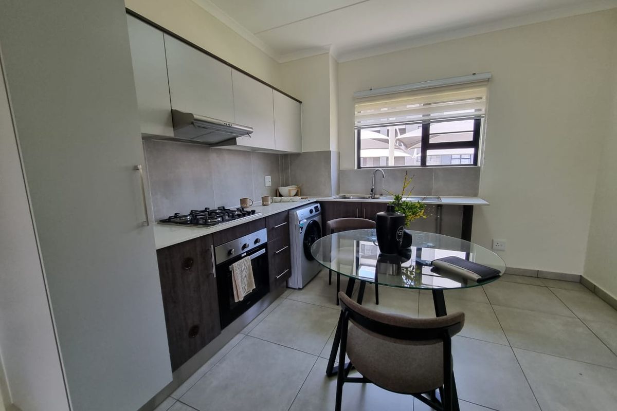 Modern kitchen featuring dark and light cabinetry, stone countertops, gas hob, built-in oven, extractor fan, and tiled flooring with an integrated laundry connection.