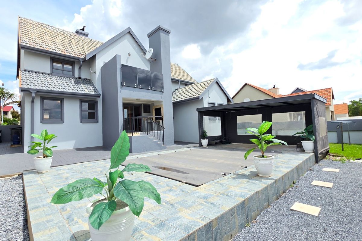 Rear exterior view featuring a tiled patio, swimming pool with cover, and a covered outdoor entertainment area attached to the main residence.
