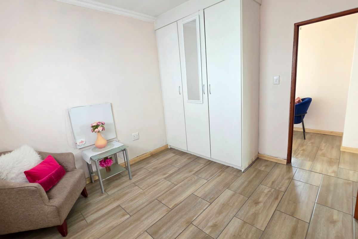 A bedroom featuring tiled flooring and a built-in wardrobe with a central mirror panel.