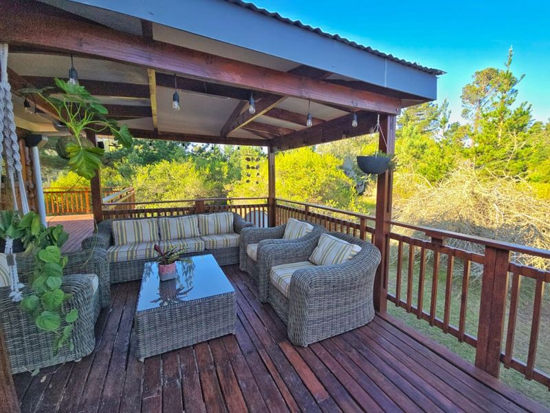 A covered outdoor timber deck featuring a pergola roof and wooden balustrade, overlooking the surrounding farm landscape.