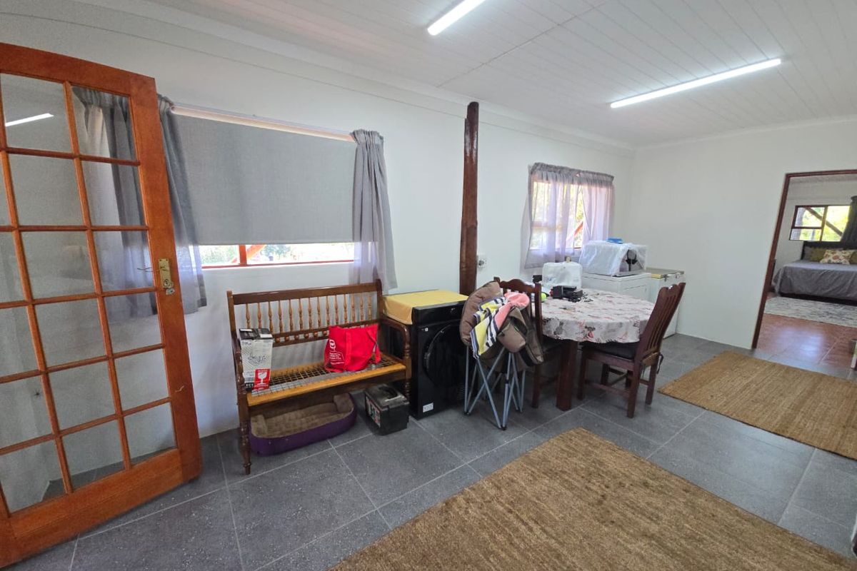 A functional living area featuring tiled flooring, timber ceiling details, and a classic timber-framed glass door leading to the exterior.
