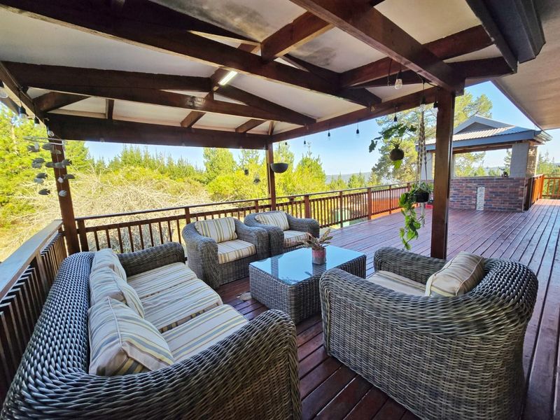 A spacious covered timber deck featuring exposed rafters and balustrades, offering an elevated outdoor living area with scenic views.