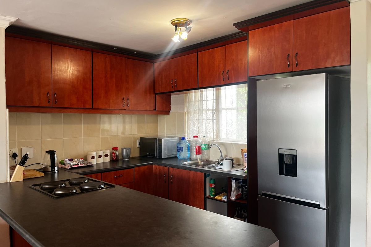 A functional kitchen featuring dark wood-finish cabinetry, dark laminate countertops, a built-in hob, and a tiled backsplash.