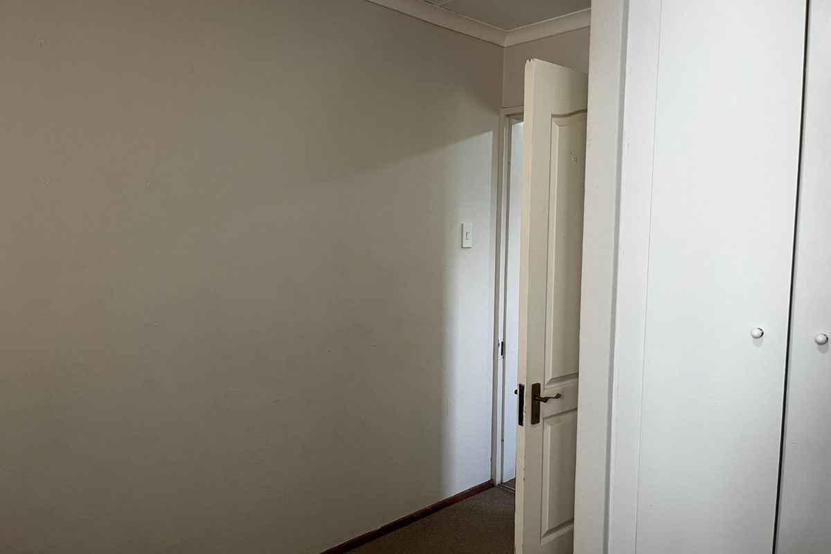 An empty bedroom featuring built-in cupboards, neutral wall finishes, and carpet flooring, providing a blank canvas for personalization.