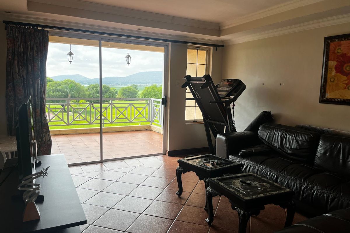 Spacious living room featuring tiled flooring, recessed lighting, and large sliding glass doors that open onto a balcony with scenic views.