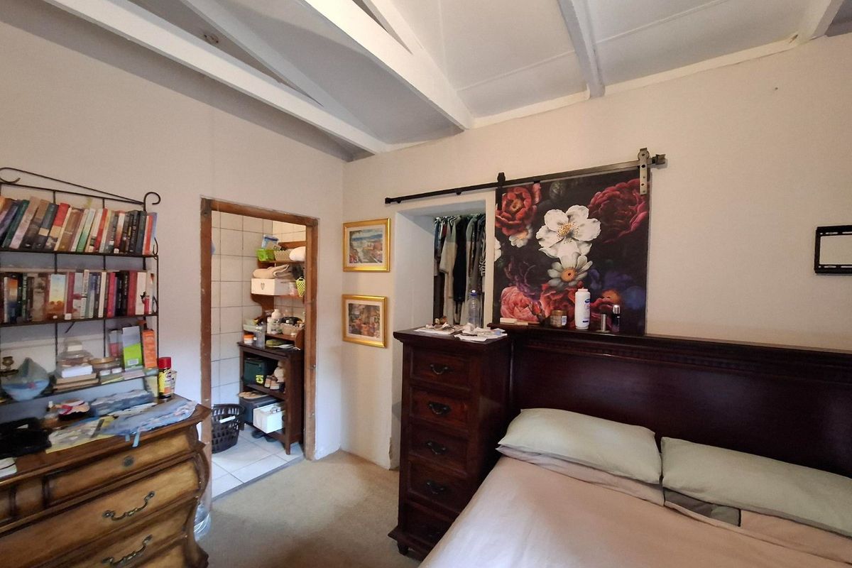 A bedroom featuring exposed ceiling beams and a sliding barn door leading to a walk-in closet area.