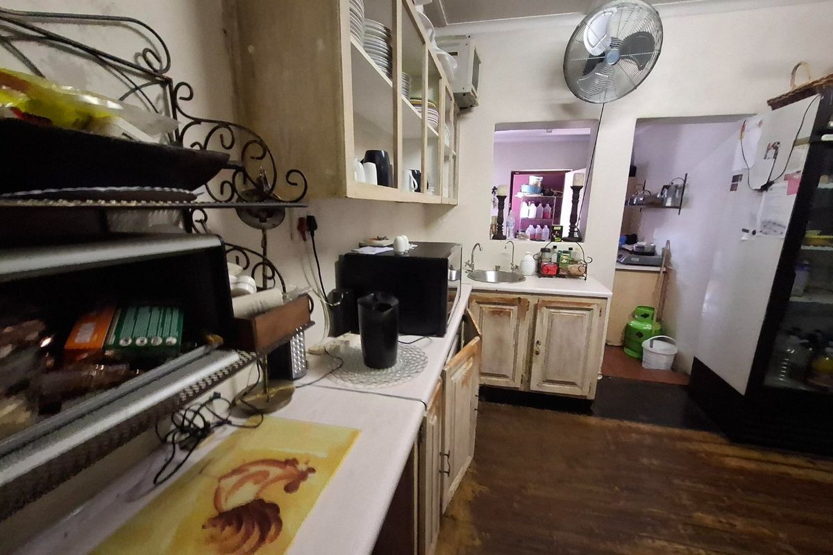 A functional kitchen space featuring built-in cabinetry, a sink, and a pass-through window, showing signs of wear and dated finishes.
