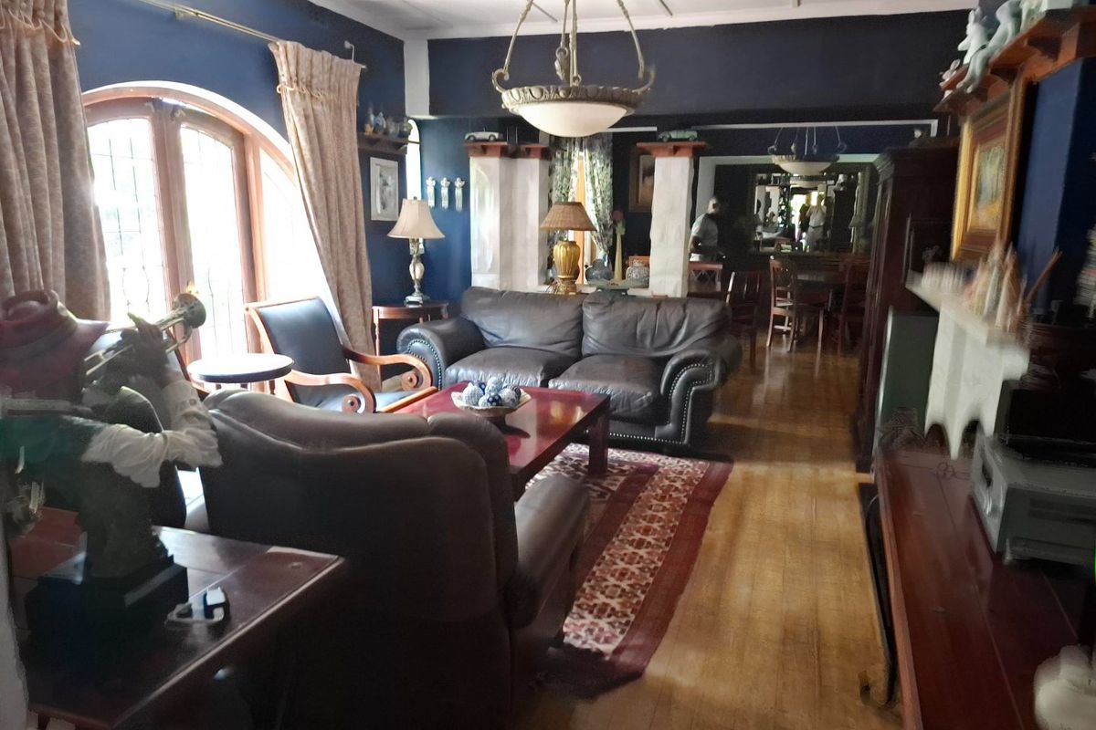 Spacious living room featuring hardwood flooring, a coffered ceiling, and an arched window, providing a classic and comfortable atmosphere.