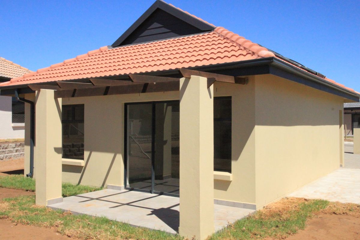 A modern rear exterior view featuring a covered patio with a timber pergola, sliding glass doors, and a well-maintained tiled roof.