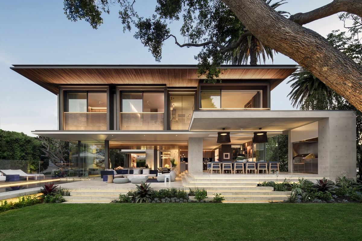 A modern luxury rear elevation featuring a spacious covered patio, built-in outdoor kitchen, seamless indoor-outdoor flow, and a beautifully landscaped garden with pool.